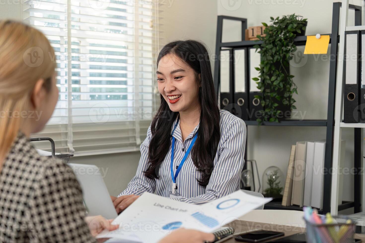 Business professional smiling while discussing a line chart with a colleague in an office photo