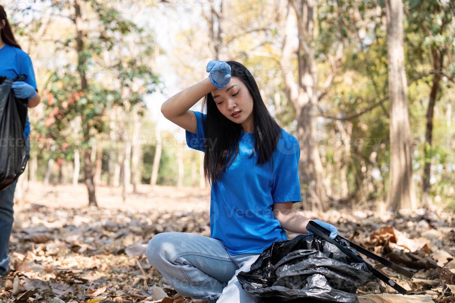 Volunteer taking a break while collecting garbage in a forest, showcasing dedication and environmental awareness photo
