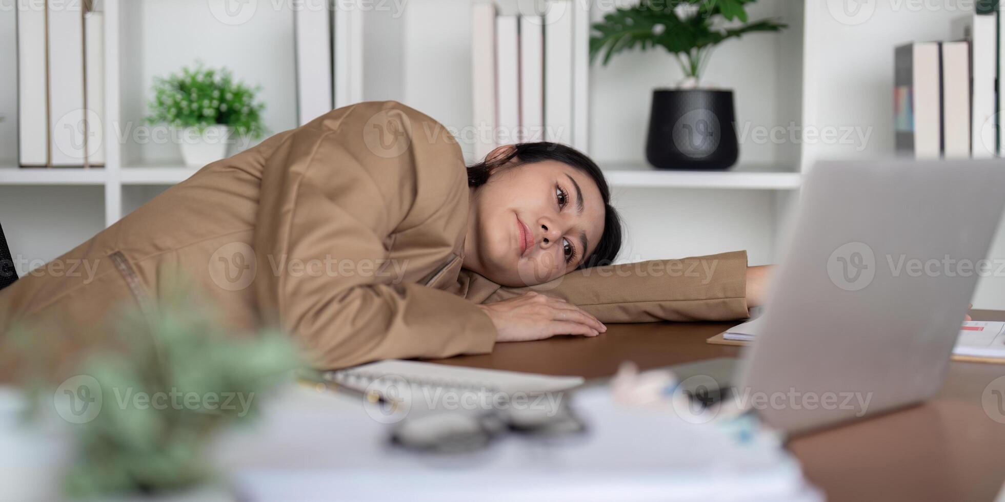 Frustrated businesswoman leaning on desk with laptop, feeling overwhelmed during a work session photo