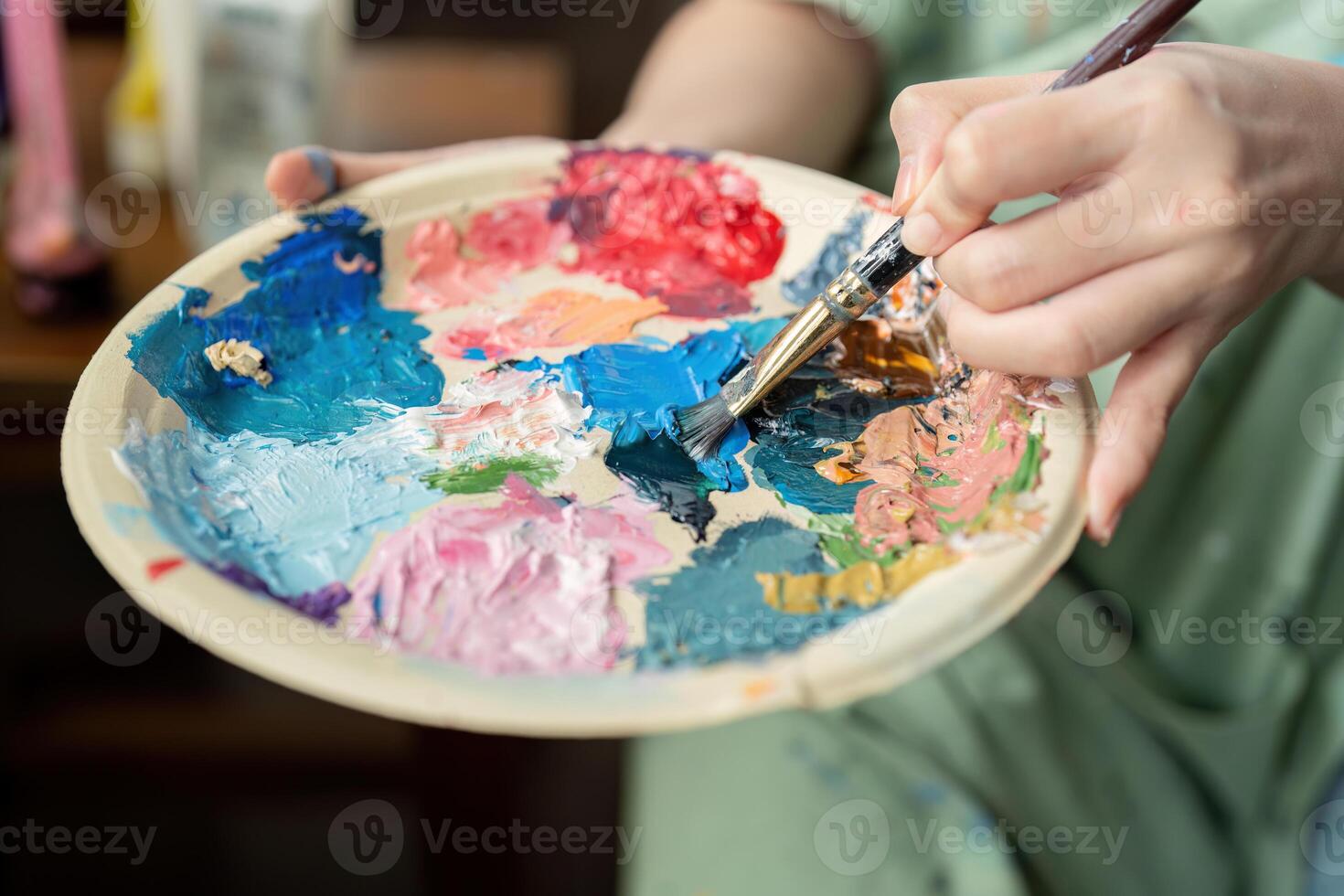 Young artist mixing vibrant colors on a palette with a brush, showcasing creativity and artistic expression photo