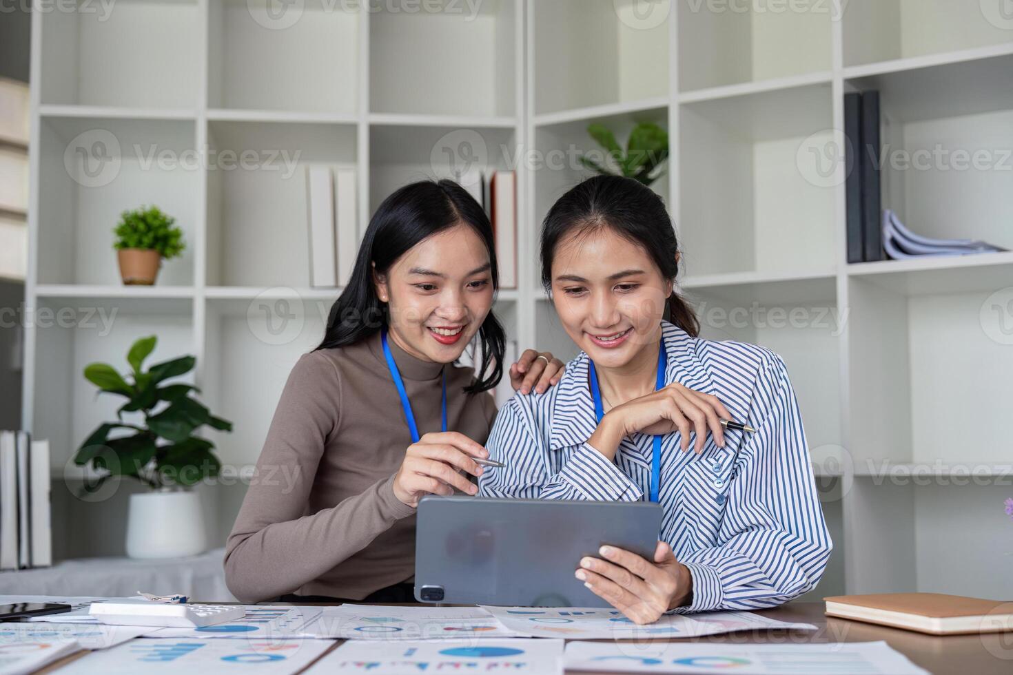 Two businesswomen reviewing project data on a tablet and sharing insights in a modern office photo