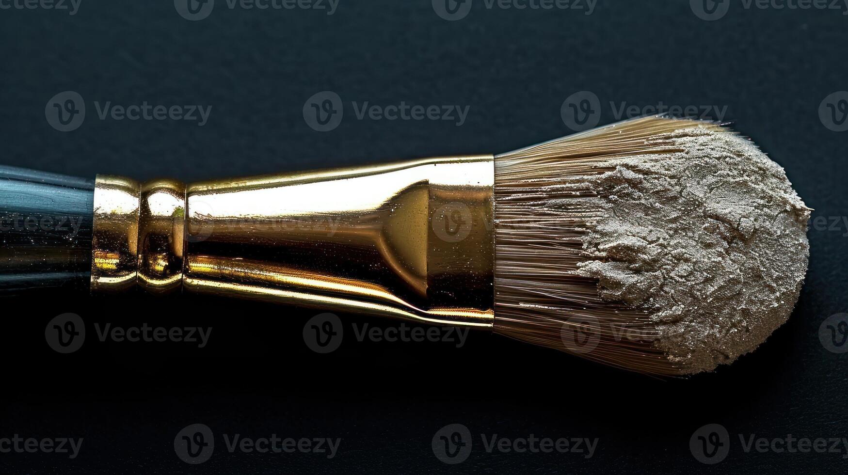 A makeup brush, golden and full of powder, against a black backdrop photo