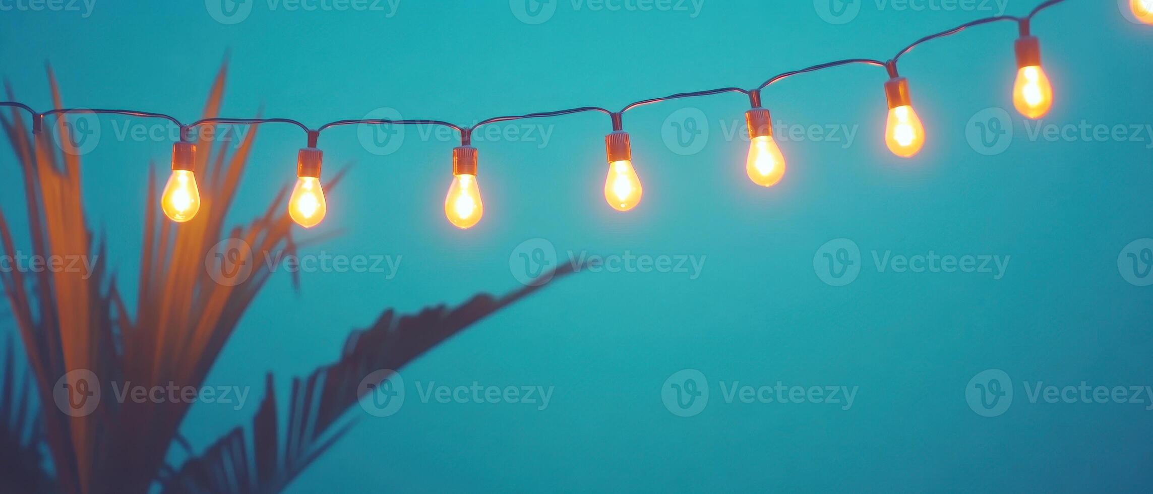 Outdoor luxury dining setup under string lights, creating warm and inviting atmosphere with glowing bulbs and tropical plants in background photo