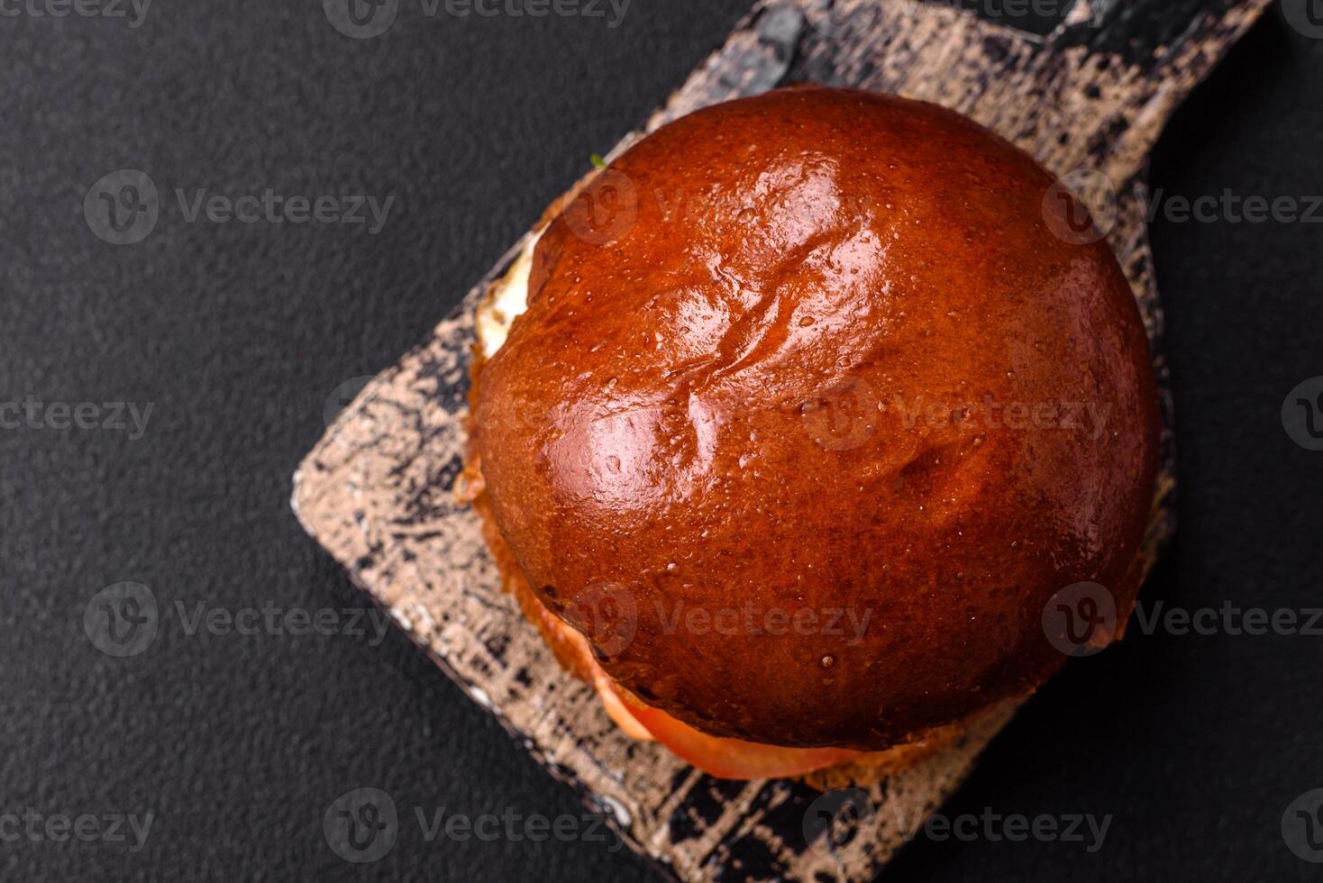 Delicious burger with beef patty, fried egg, bacon, herbs, sauce, sal and spices photo