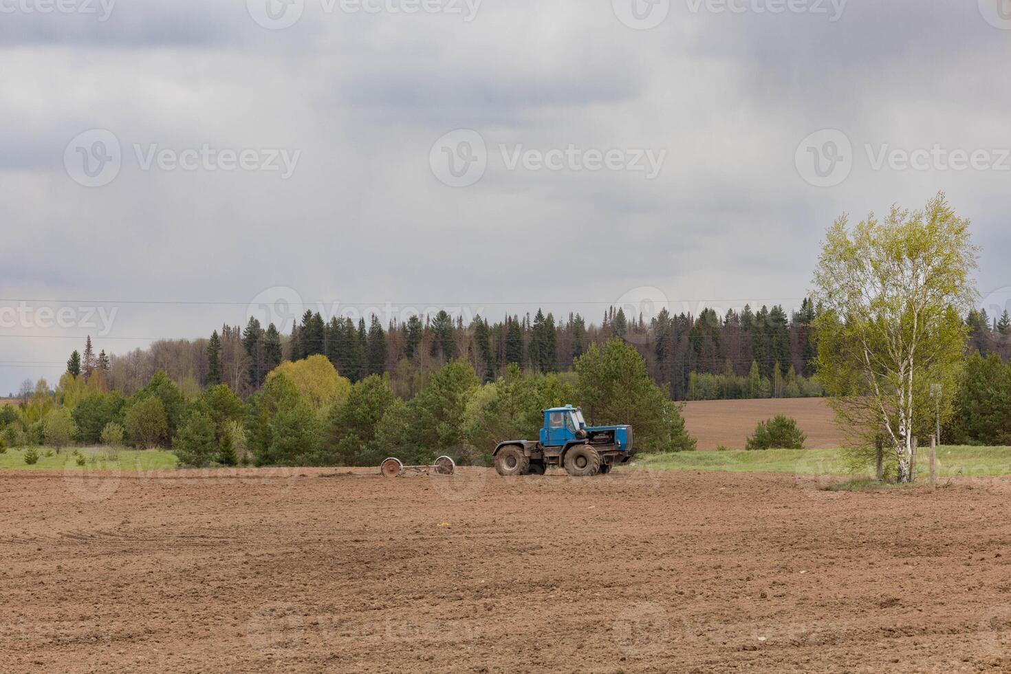 A farmer on a tractor plows a field in the spring photo