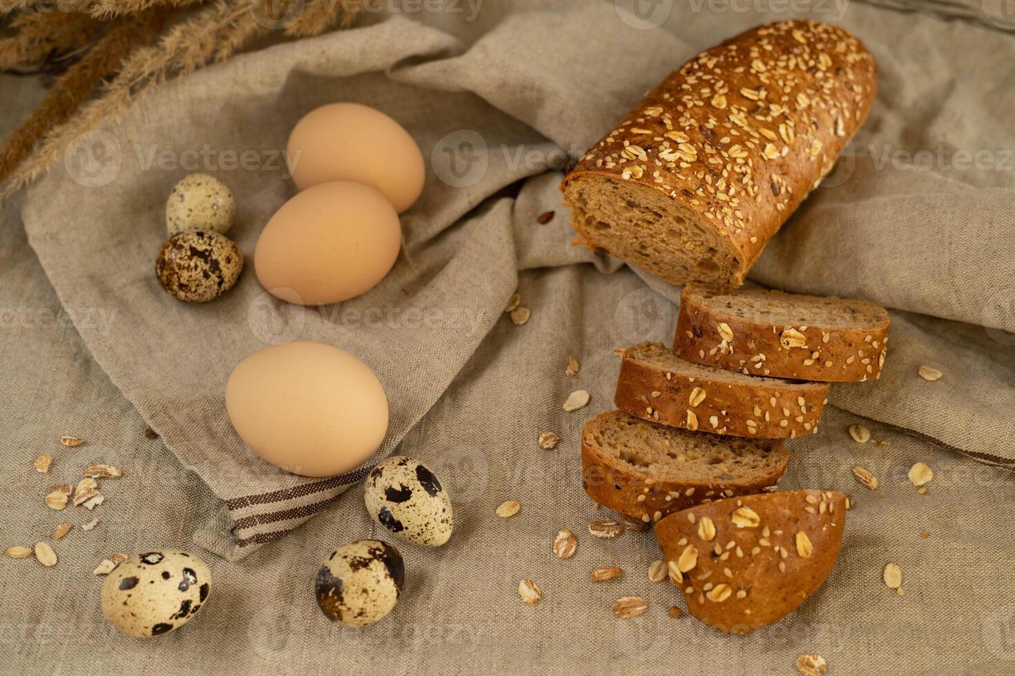 Smooth cereal baguette with sunflower seeds, chicken eggs and quail natural fresh farm eggs on a linen towel photo