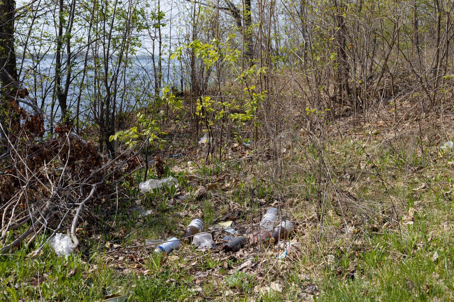 Riverbank, polluted with rubbish, a sunny spring day photo