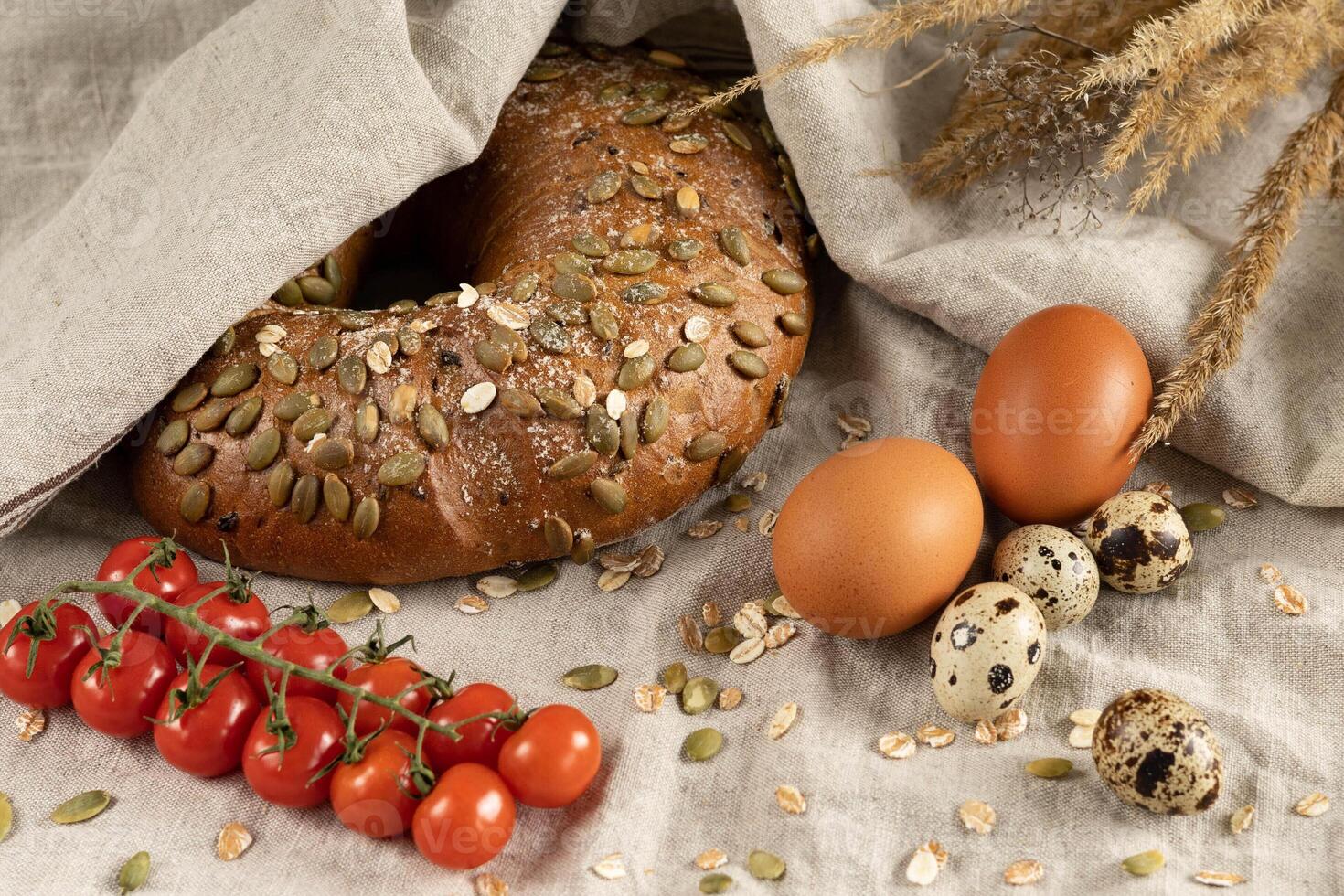 Bread rye cereal lean round, eggs chicken and quail fresh natural farm, cherry tomatoes small on tablecloth photo
