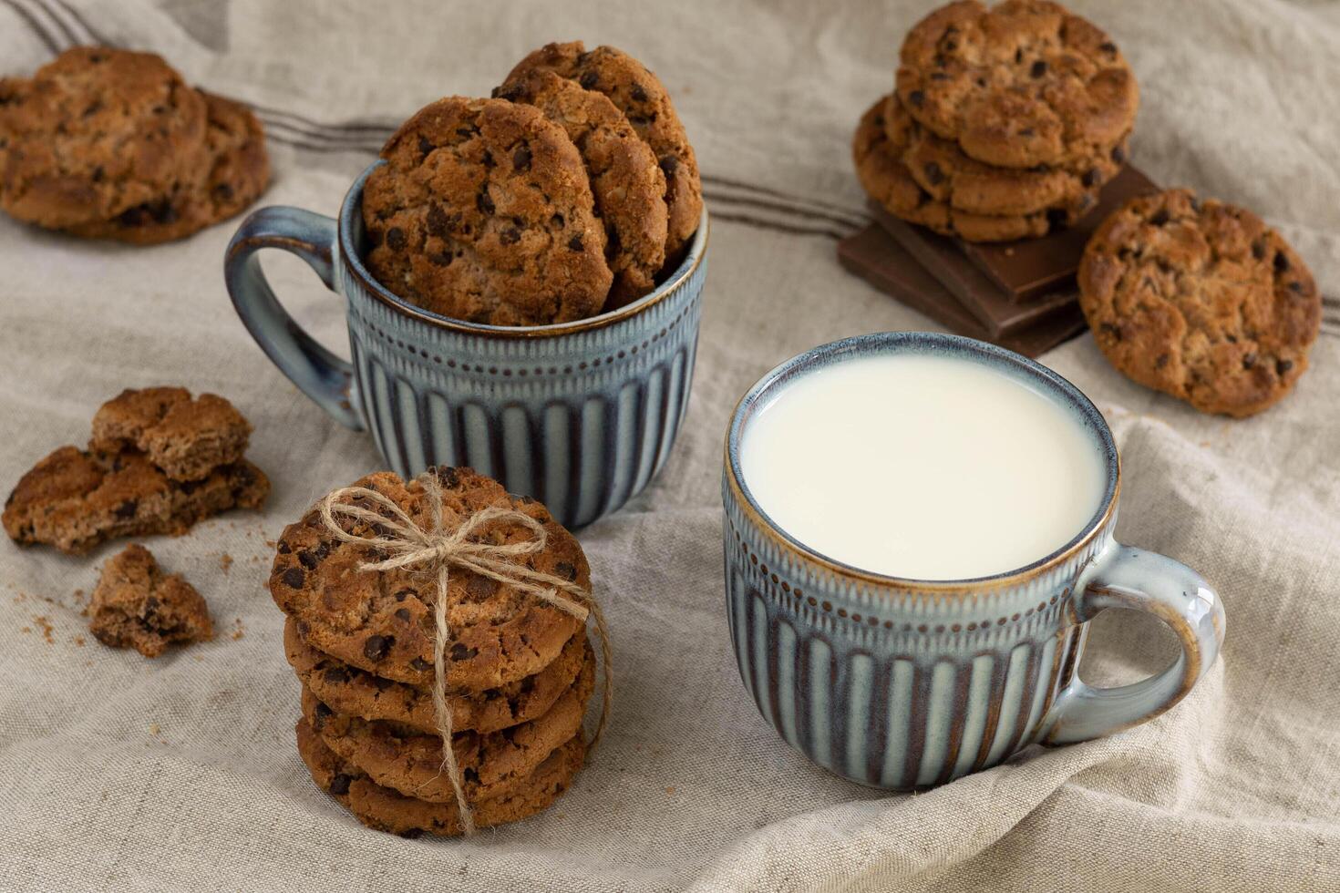 Homemade oatmeal cookies, chocolate chunks, blue cup of milk photo