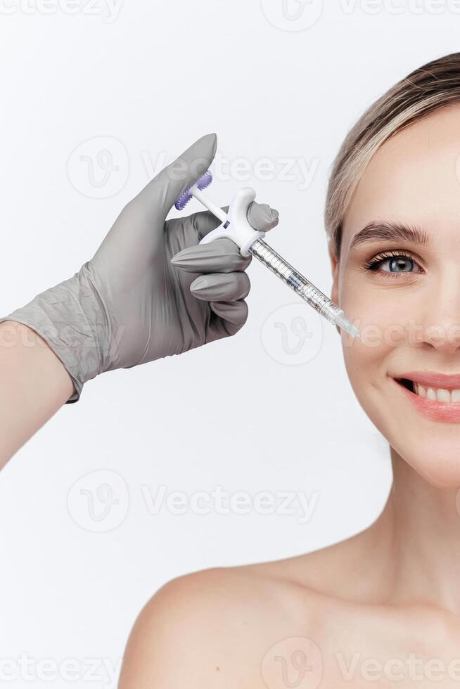 Closeup of young woman receiving hyaluronic acid injection isolated on white background. Beautician doing beauty procedure to female face with syringe. Lifting, collagen in lip area. Vertical shot photo
