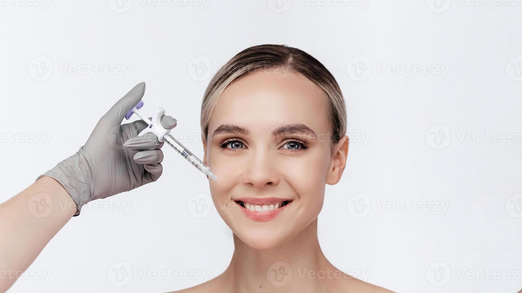 Closeup of young woman receiving hyaluronic acid injection isolated on white background. Beautician doing beauty procedure to female face with syringe. Lifting, collagen in lip area. Cosmetology ads photo