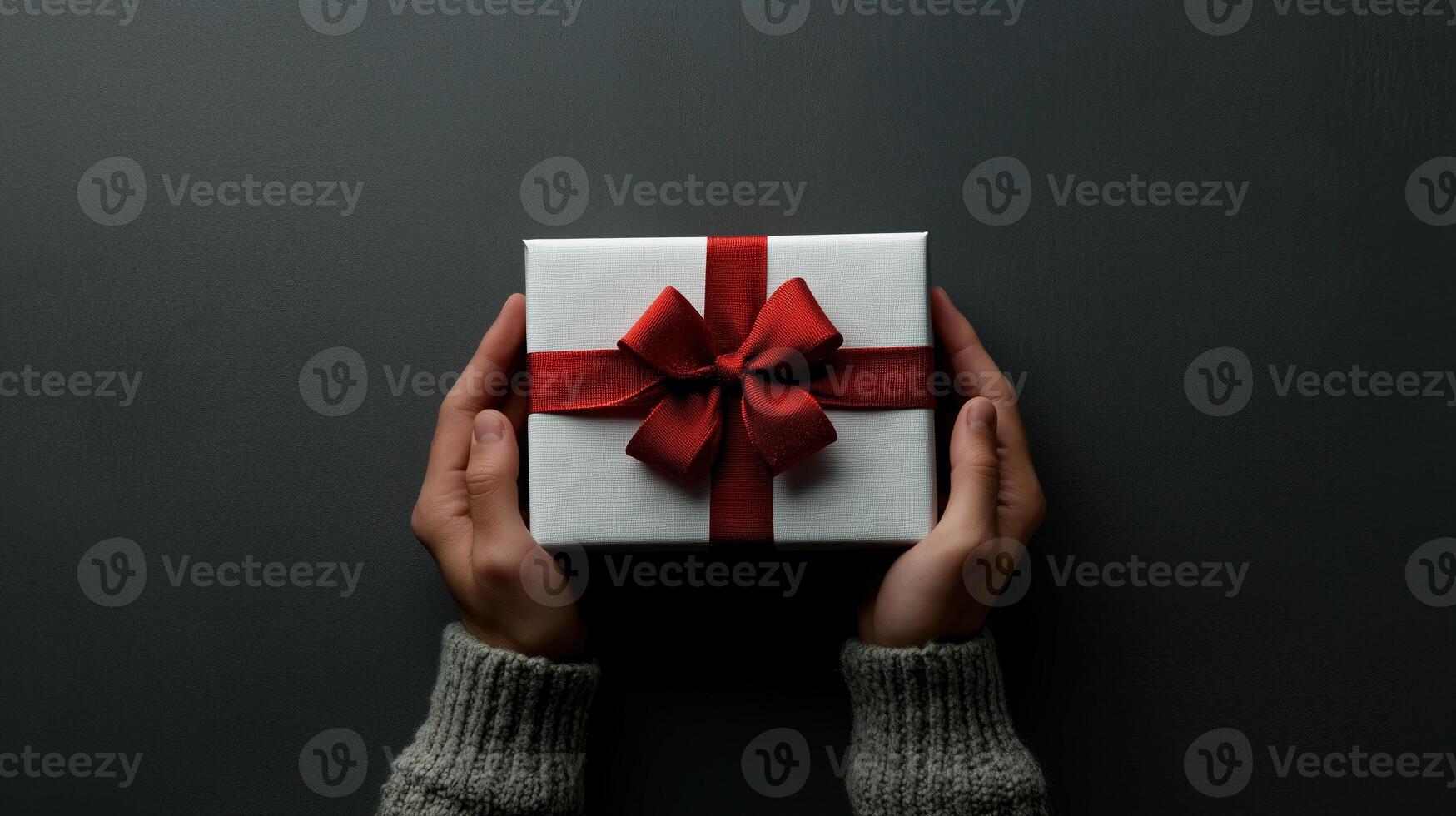 Male hands holding a white gift box with a red ribbon, against a gray background, ideal for themes of holiday. L1 photo