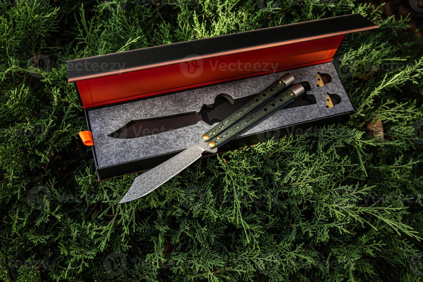 A beautifully crafted butterfly knife with a patterned blade and green handle, displayed in an elegant box with a foam insert. photo