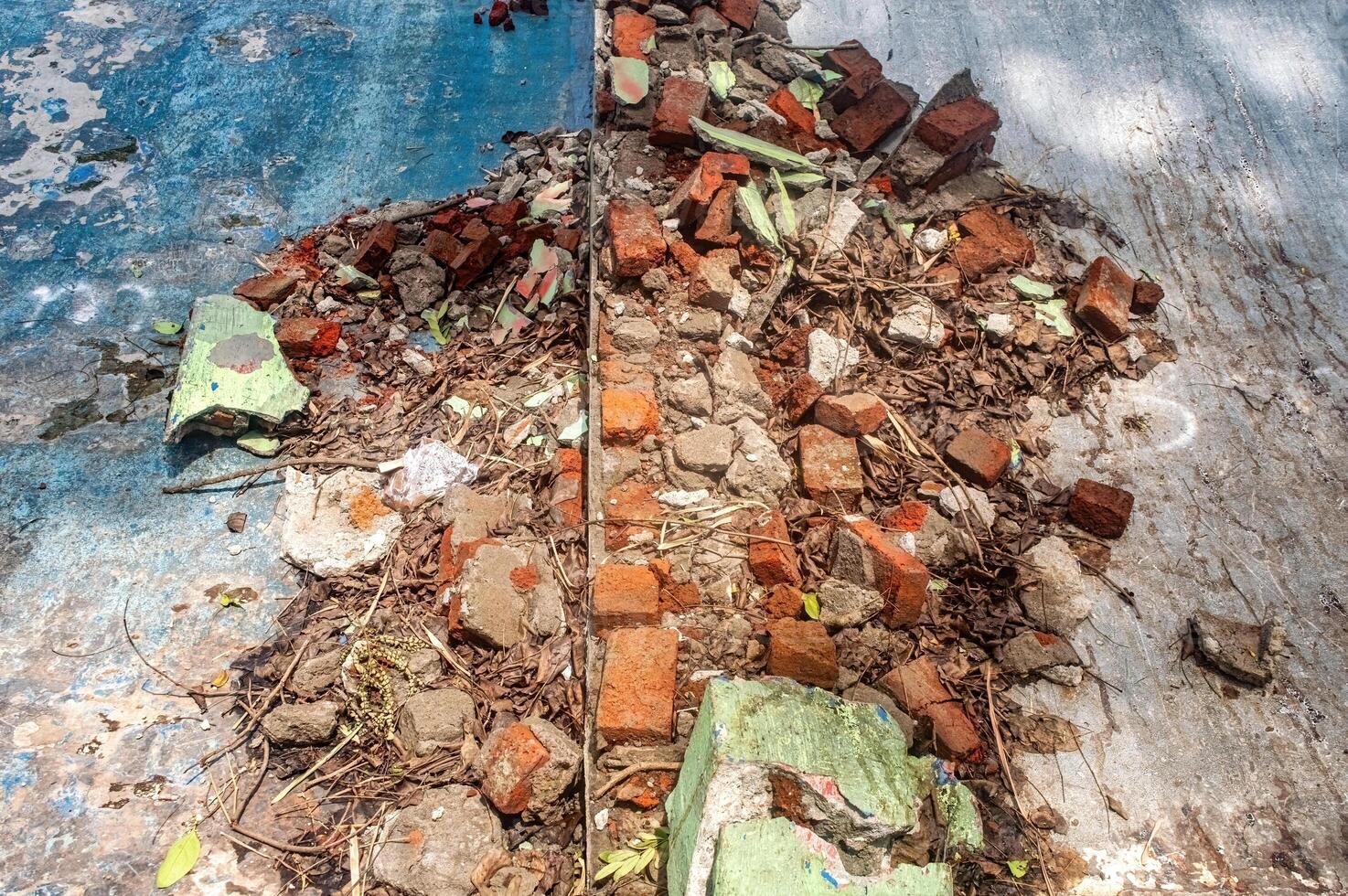A pile of broken bricks, concrete, and debris on a weathered, blue-painted surface. This image depicts decay and abandonment, perfect for construction or urban decay themes photo