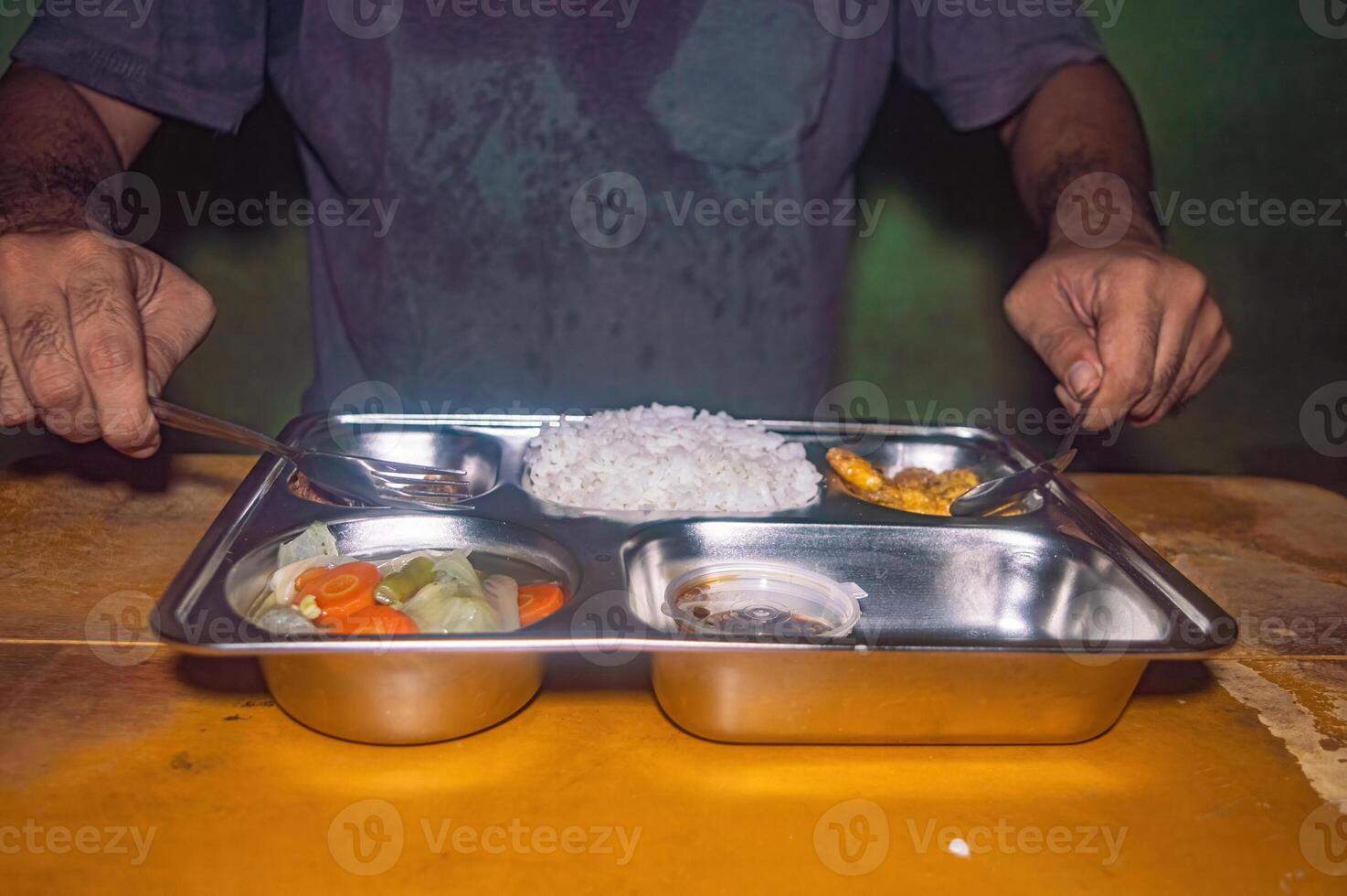 A person is having a nutritious and healthy free lunch consisting of rice, vegetables, and a side dish on a stainless steel tray, showcasing a balanced meal photo