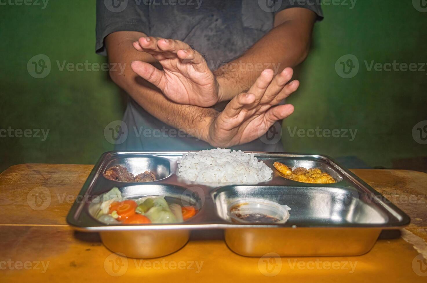 A person is refusing a meal consisting of rice, vegetables, and meat on a metal tray, highlighting the concept of free or nutritious and healthy lunch photo