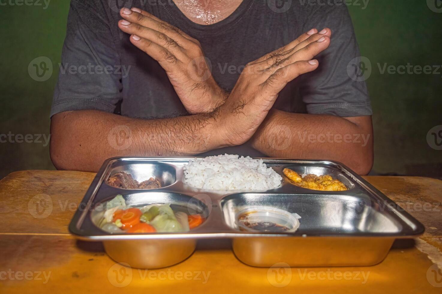 A person is refusing a meal on a tray containing rice, vegetables, and meat. This image represents the concept of free lunch or healthy and nutritious eating photo