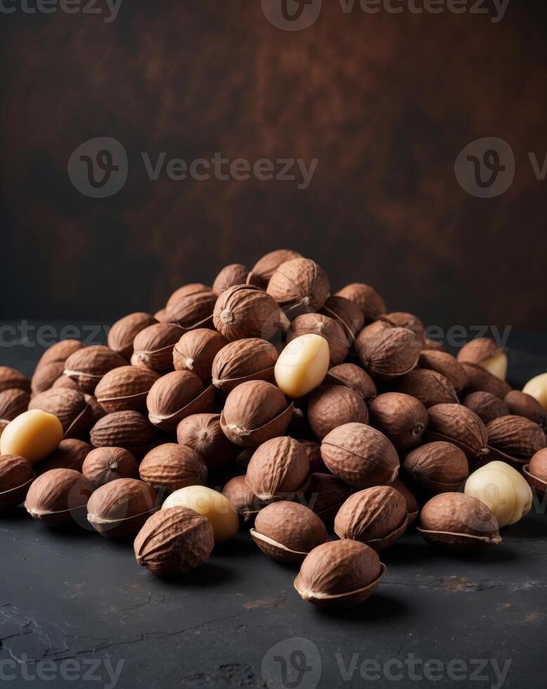 Pile of Brown Macadamia Nuts with Shells on Dark Background. photo