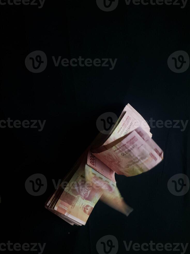Indonesian Rupiah bills falling in dynamic motion against a dark backdrop photo