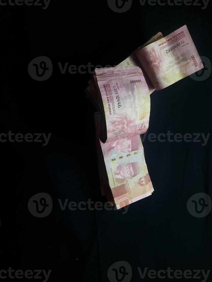 Stack of Indonesian Rupiah currency notes on a dark surface in a still life composition photo