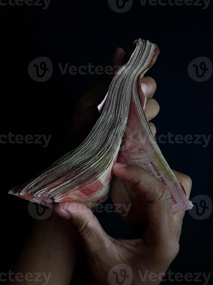 Stacks of Indonesian Rupiah Banknotes on a table Black Surface Hand Holding Cash photo