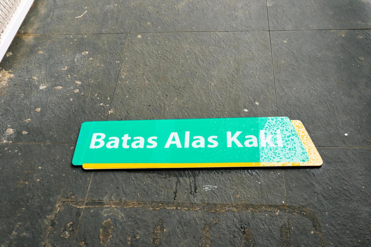 Bakauheni, January 17, 2025, Signage on gray tiled floor with text Batas Alas Kaki photo