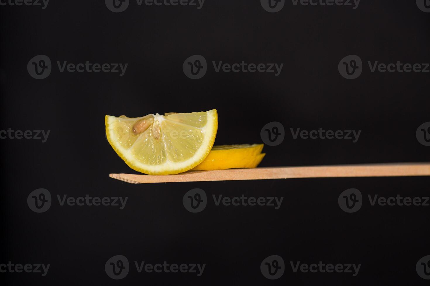 Lemons and vitamins. slice of fresh juicy lemon on wooden spatula isolated on black background photo