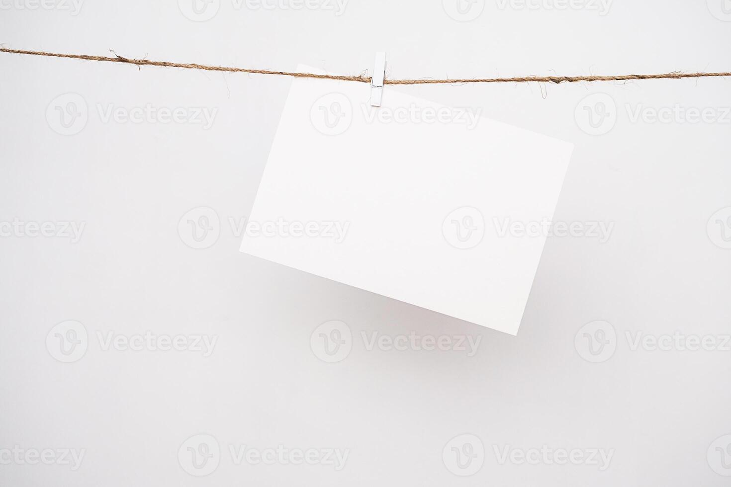 Mockup sheet paper. White card hanging on rope by pin. photo