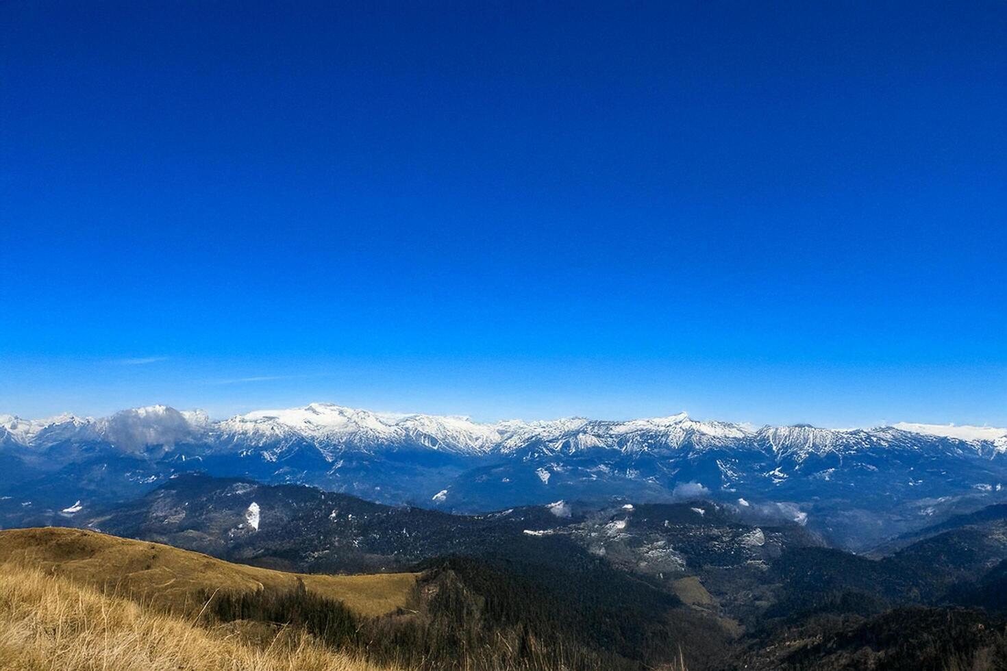 Mountain range panorama, clear sky, snow-capped peaks, autumnal foreground photo