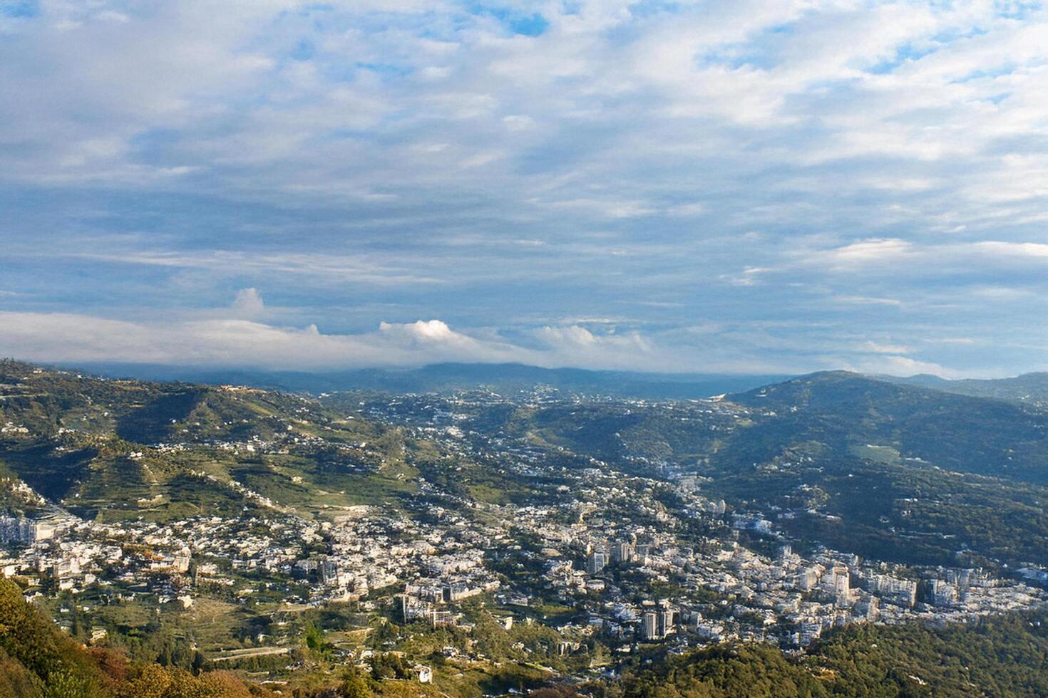 Hilltop Cityscape Aerial view of a Mediterranean town nestled in mountains under a partly cloudy sky photo