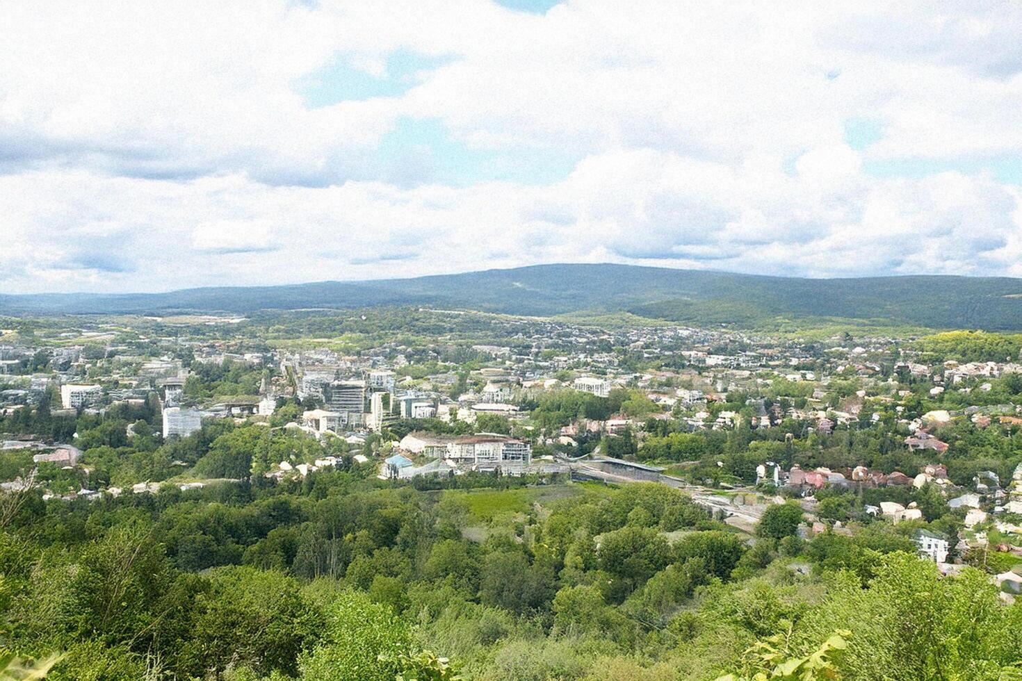 Hilltop view Cityscape panorama, lush green valley, cloudy sky photo
