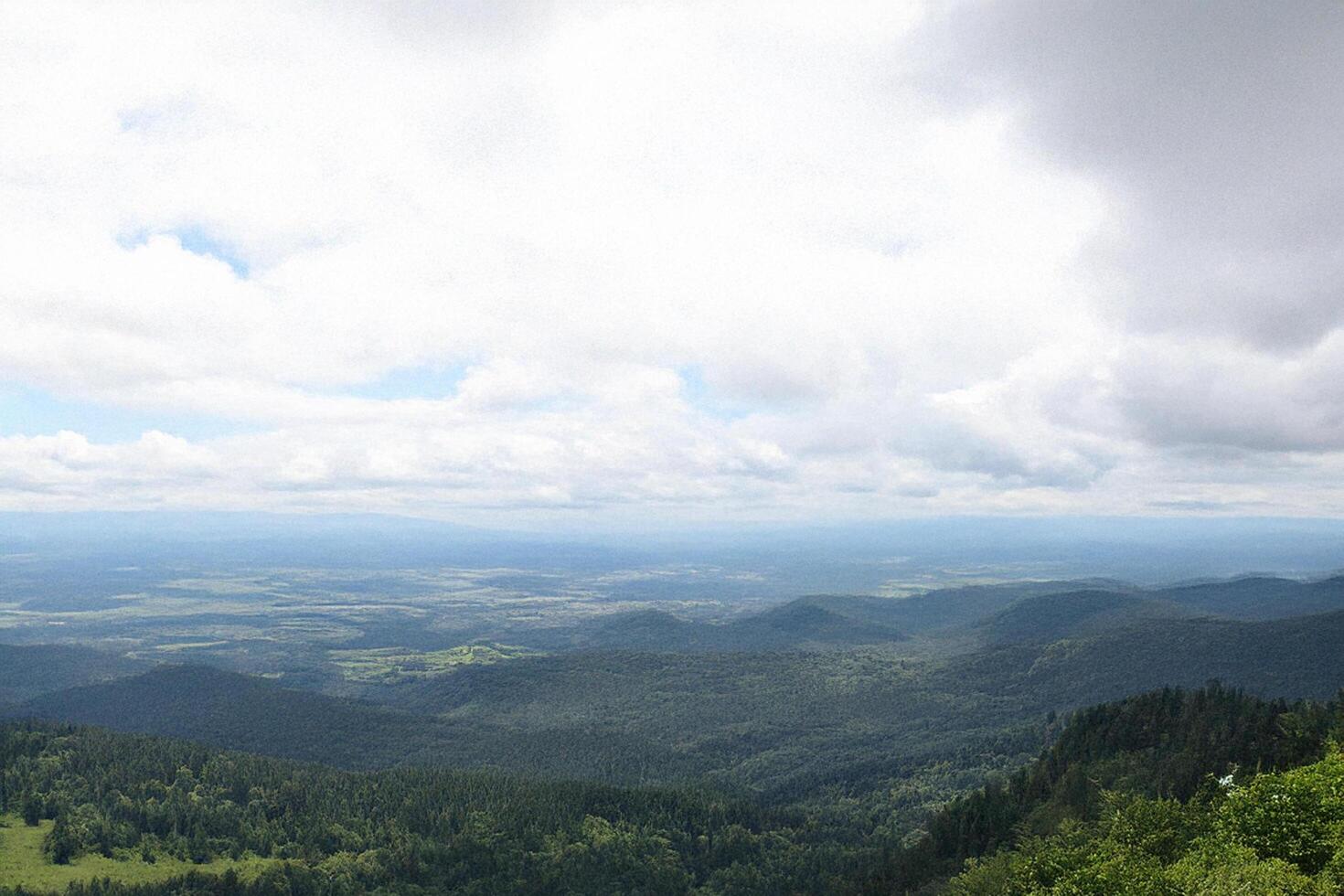 Mountaintop panoramic view cloudy sky, rolling hills, distant valley photo