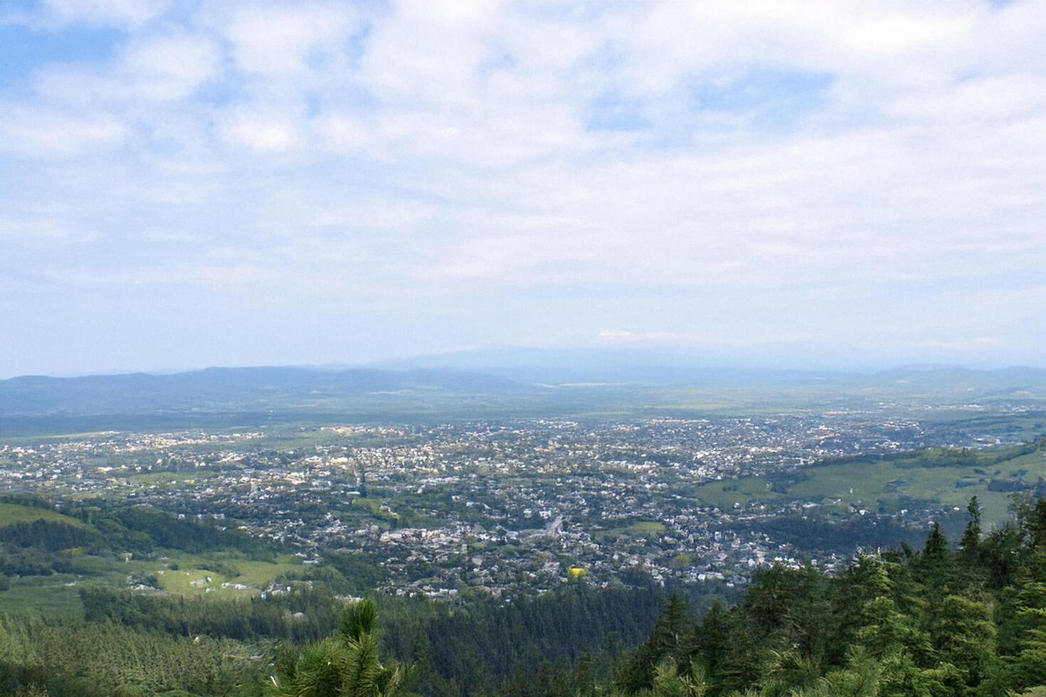 Mountaintop panoramic view of valley town, cloudy sky photo