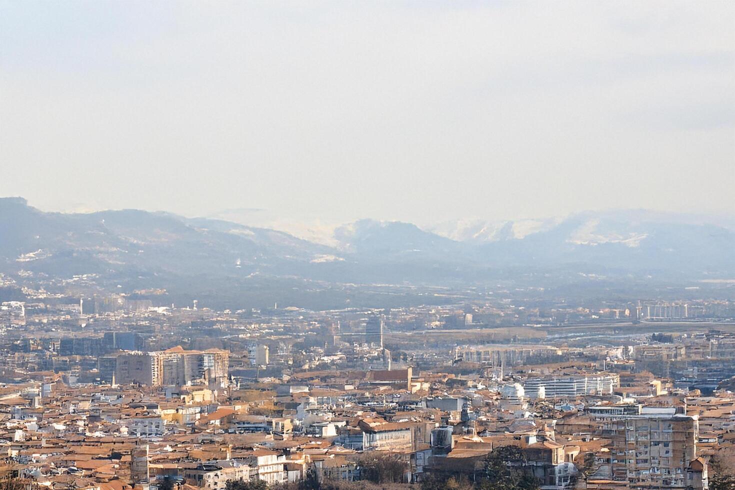 Cityscape view, mountain backdrop, hazy day, travel brochure photo