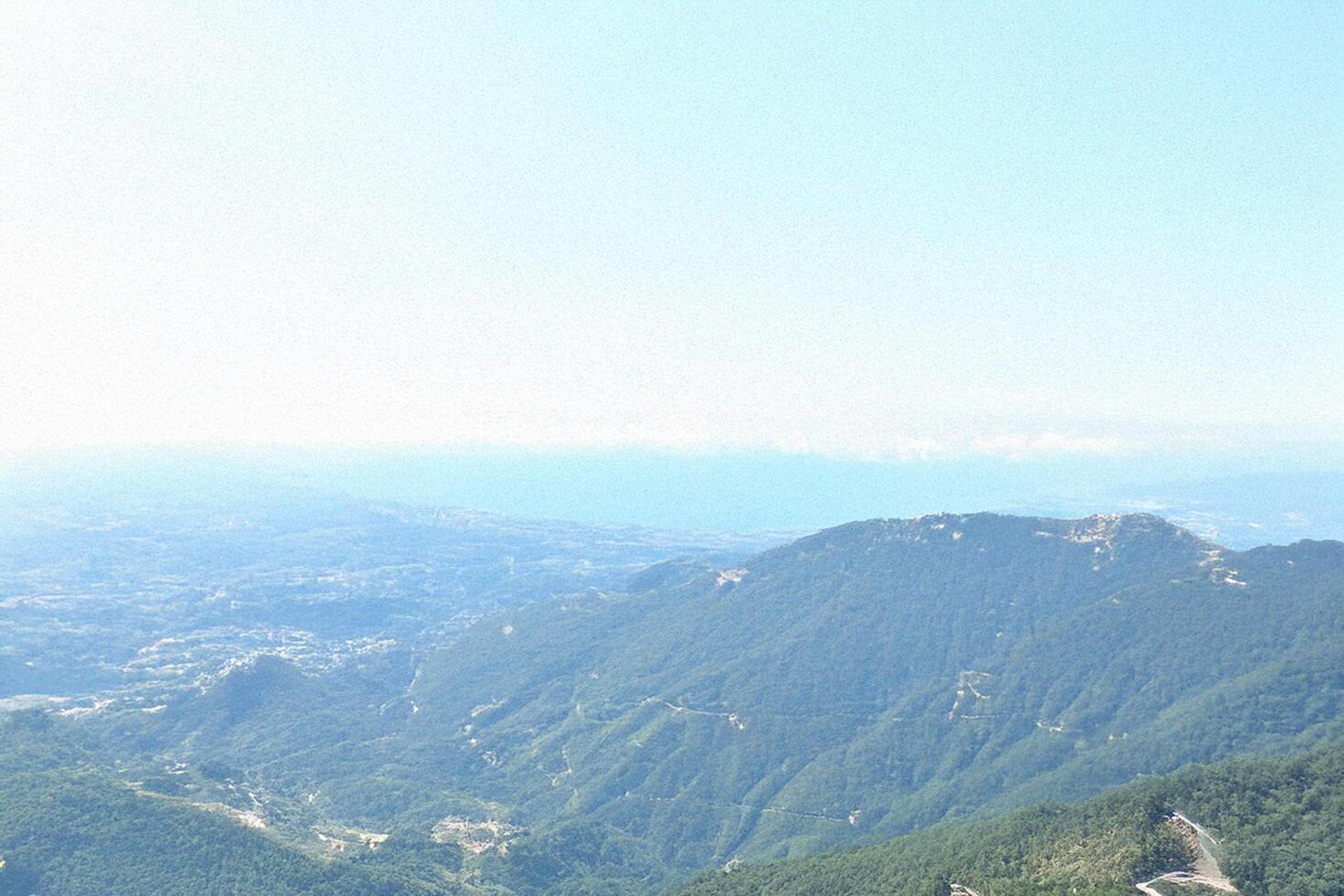 Mountaintop panorama coastal view, hazy sky, distant city photo