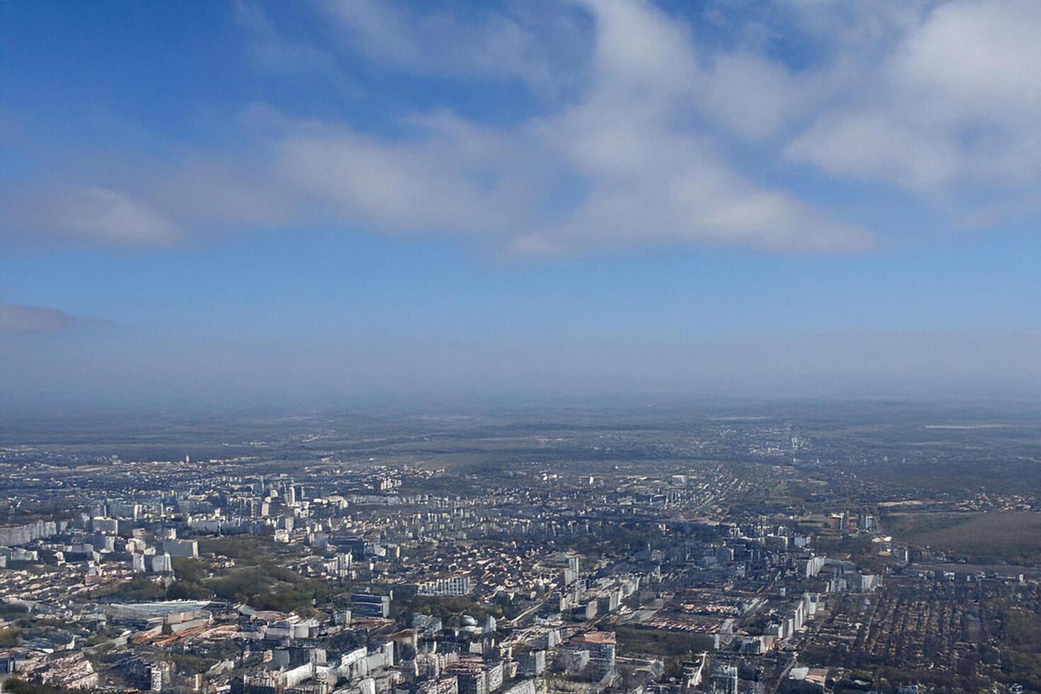 Aerial city view, hazy horizon, mountain backdrop, urban landscape, travel brochure photo