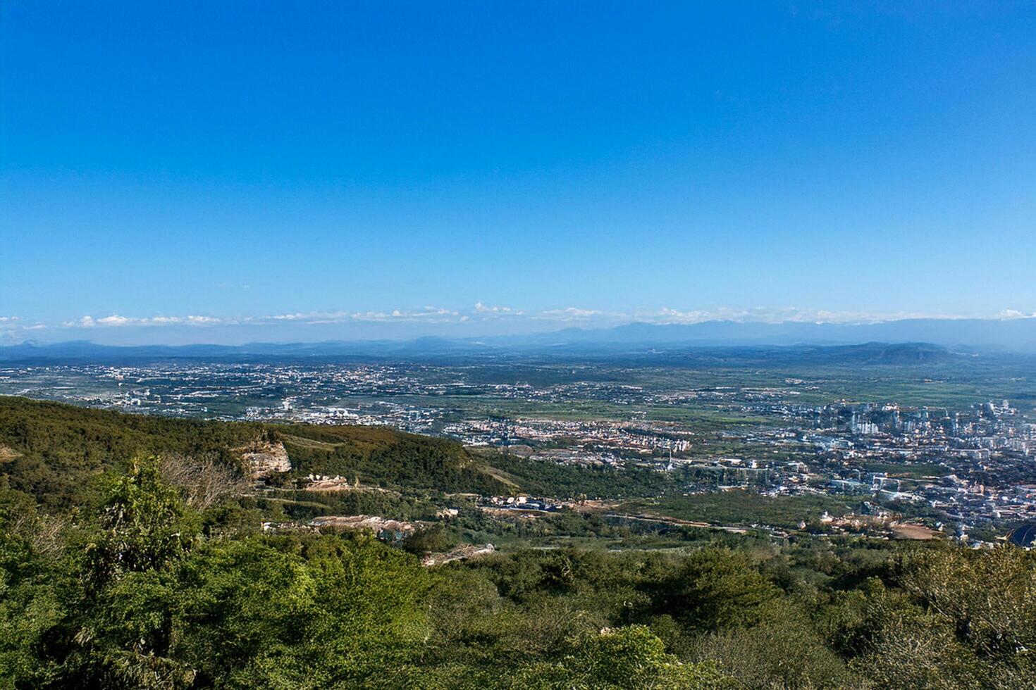 Hilltop panoramic city view, sunny day, distant mountains photo