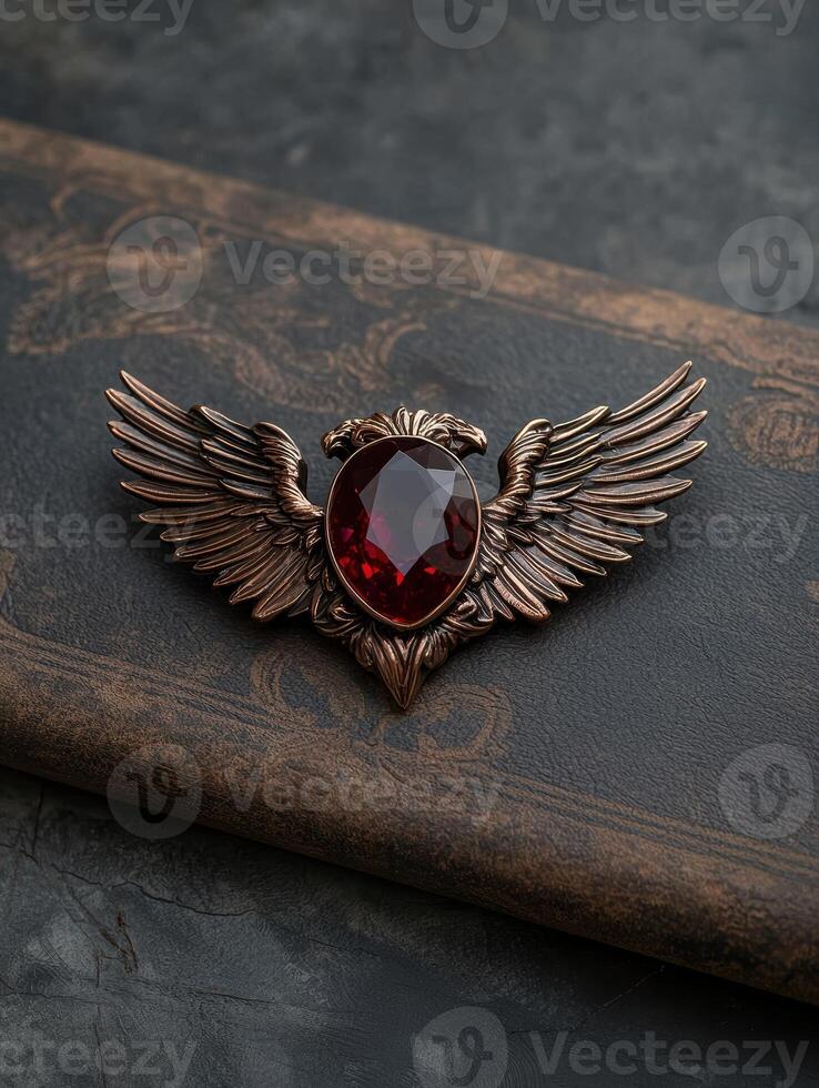 Red gemstone eagle wing brooch on brown leather background photo