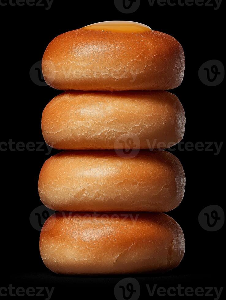 Stack of four honey glazed buns on black background photo