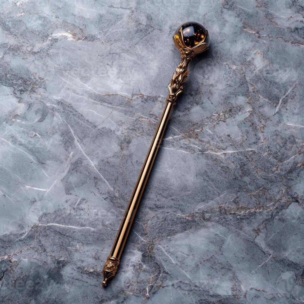 Golden ornate scepter with a crystal ball top on a marble background photo