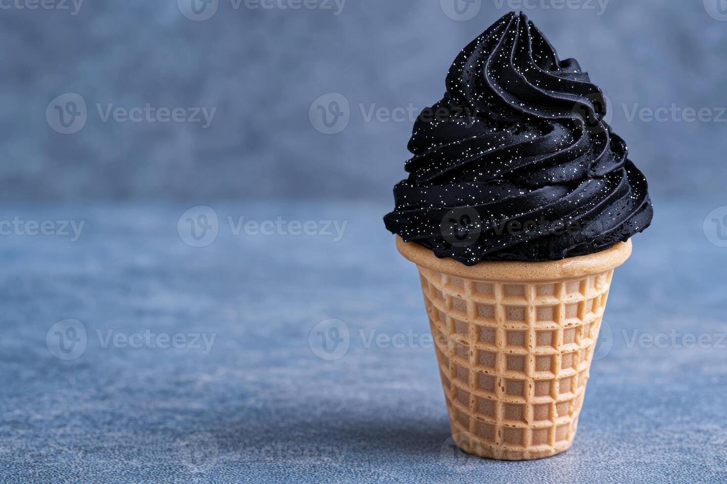 Black ice cream cone with glitter on a blue background photo