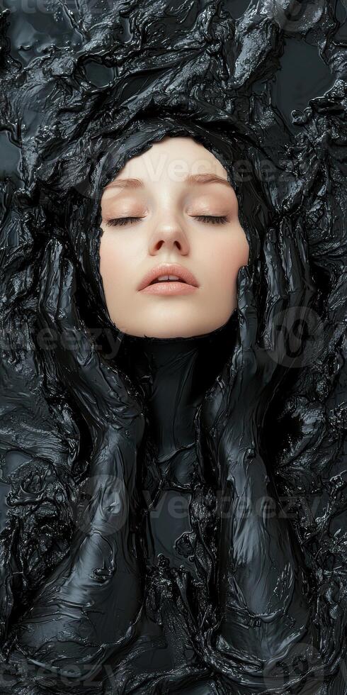 Woman with eyes closed, face covered in black mud mask photo
