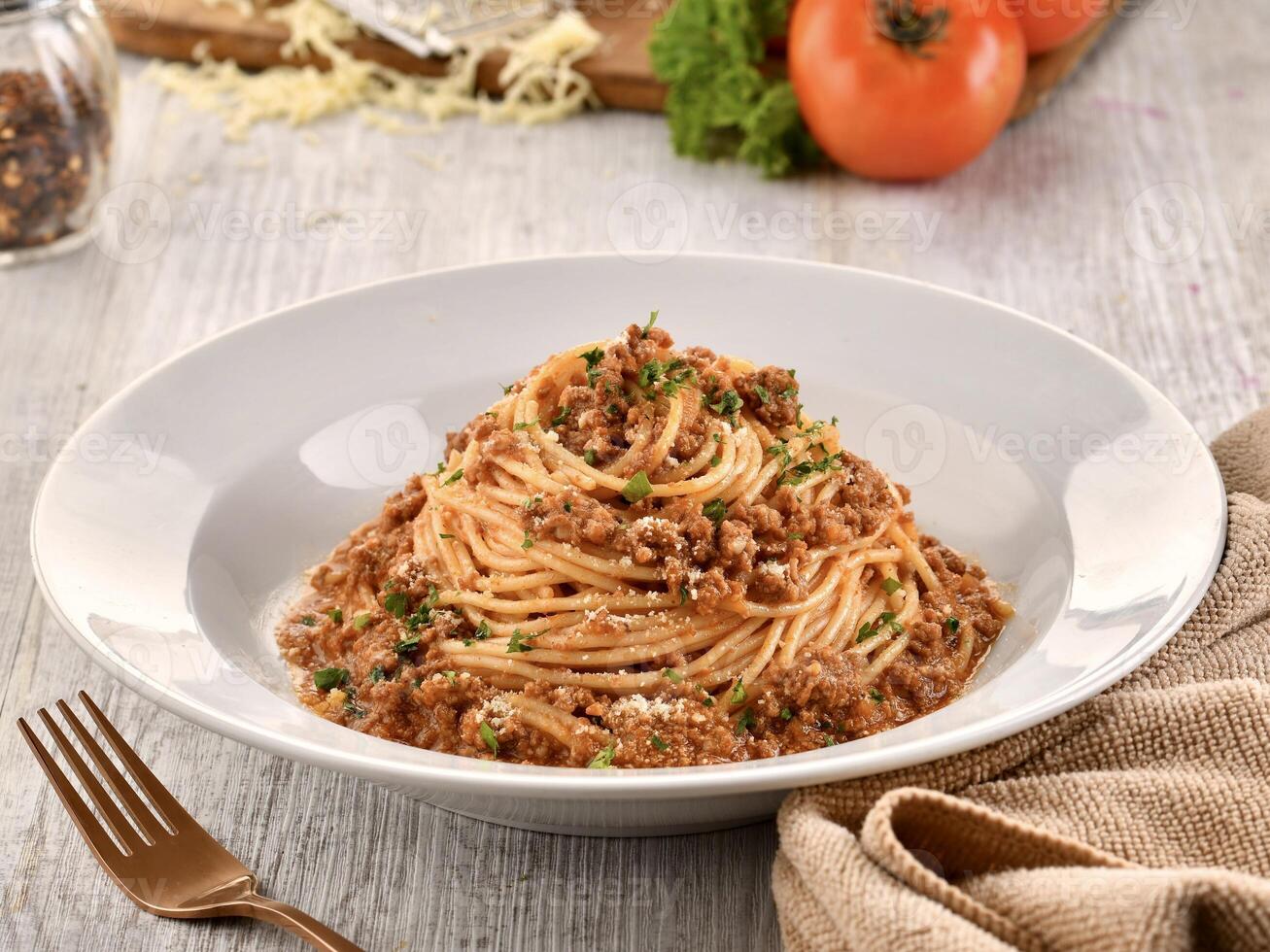 SPAGHETTI BOLOGNESE with fork served in dish isolated on wooden table side view of italian fast food photo