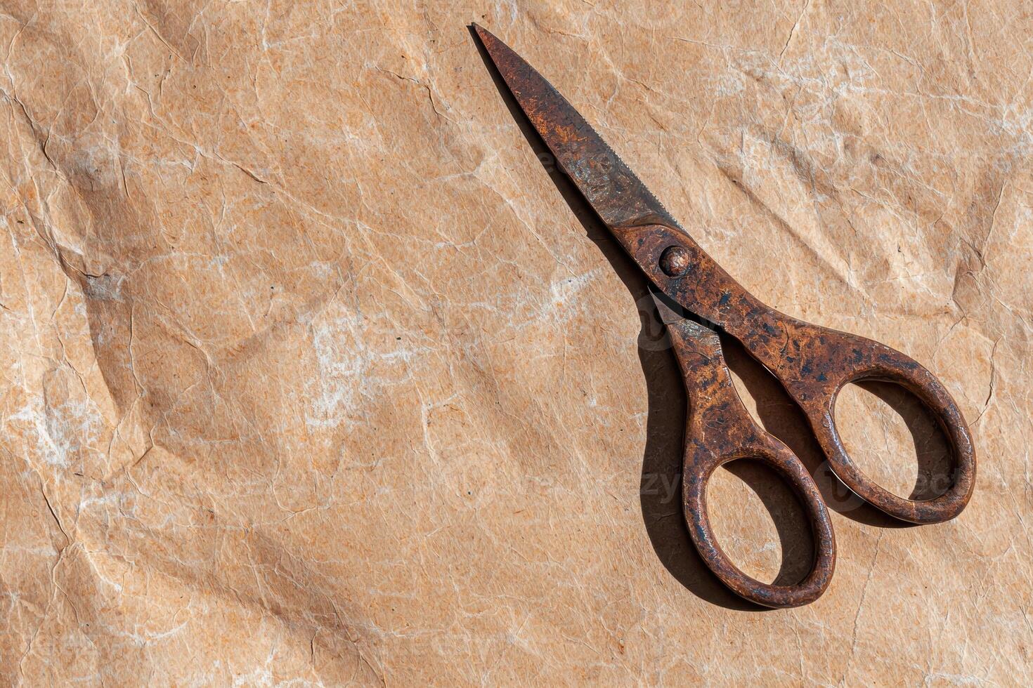 Rusty scissors on crumpled brown paper background photo