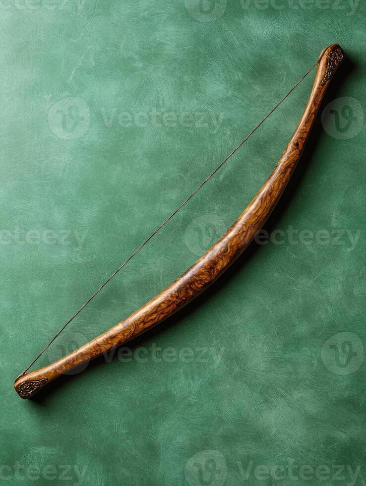 Antique wooden bow with intricate carvings on a green background photo