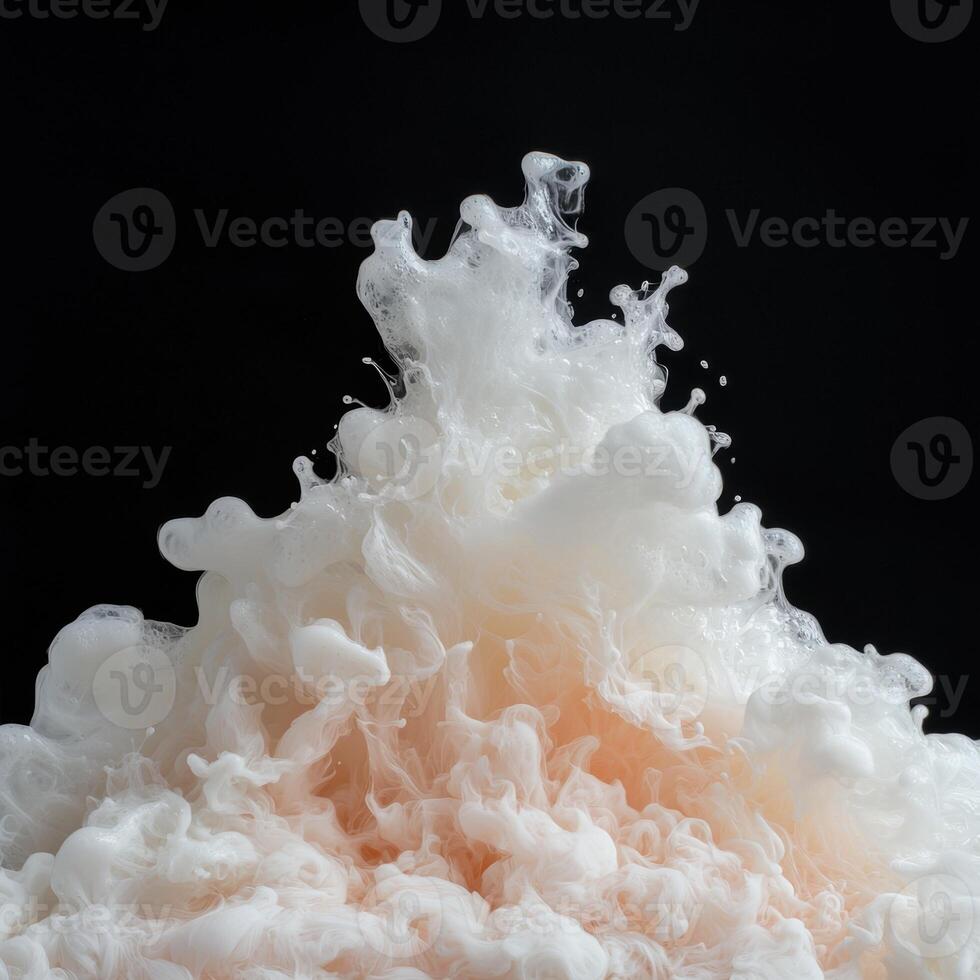 Abstract white and peach ink swirling in water, black background photo