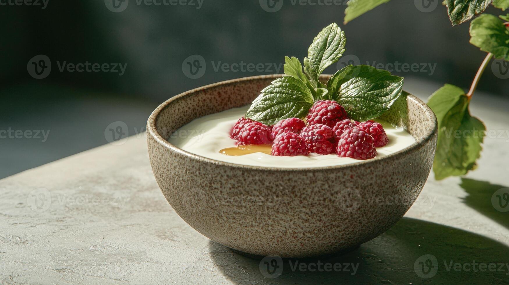 Close up of a bowl of creamy yogurt topped with fresh raspberries and a sprig of mint photo