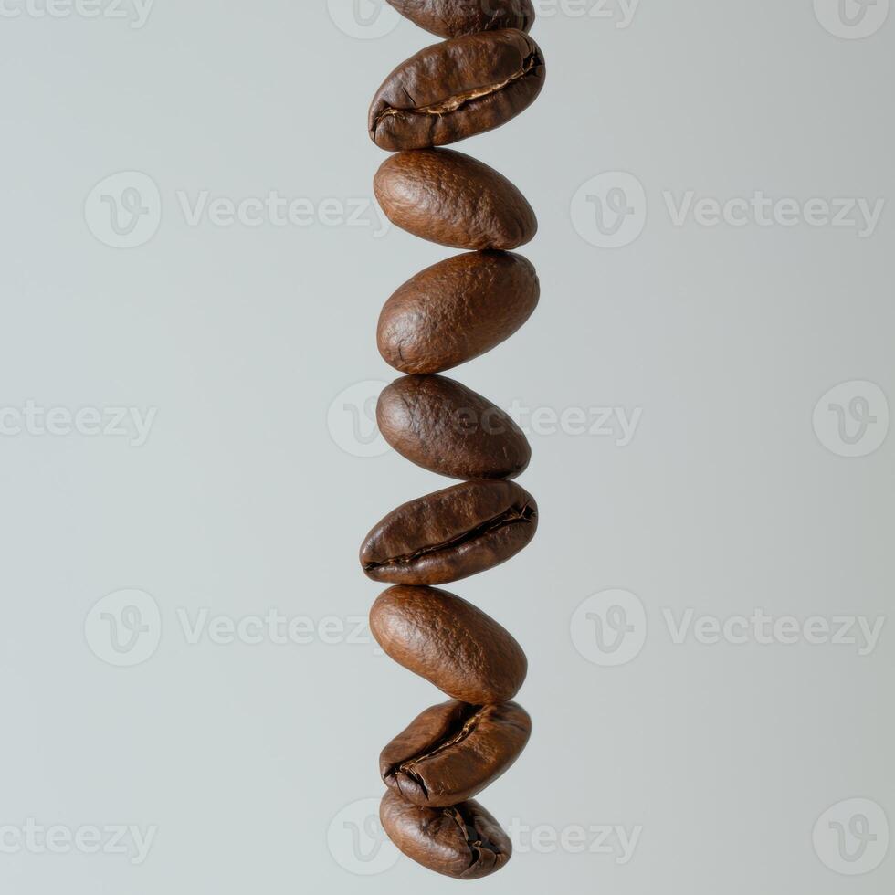Close up of a vertical line of roasted coffee beans against a light gray background photo