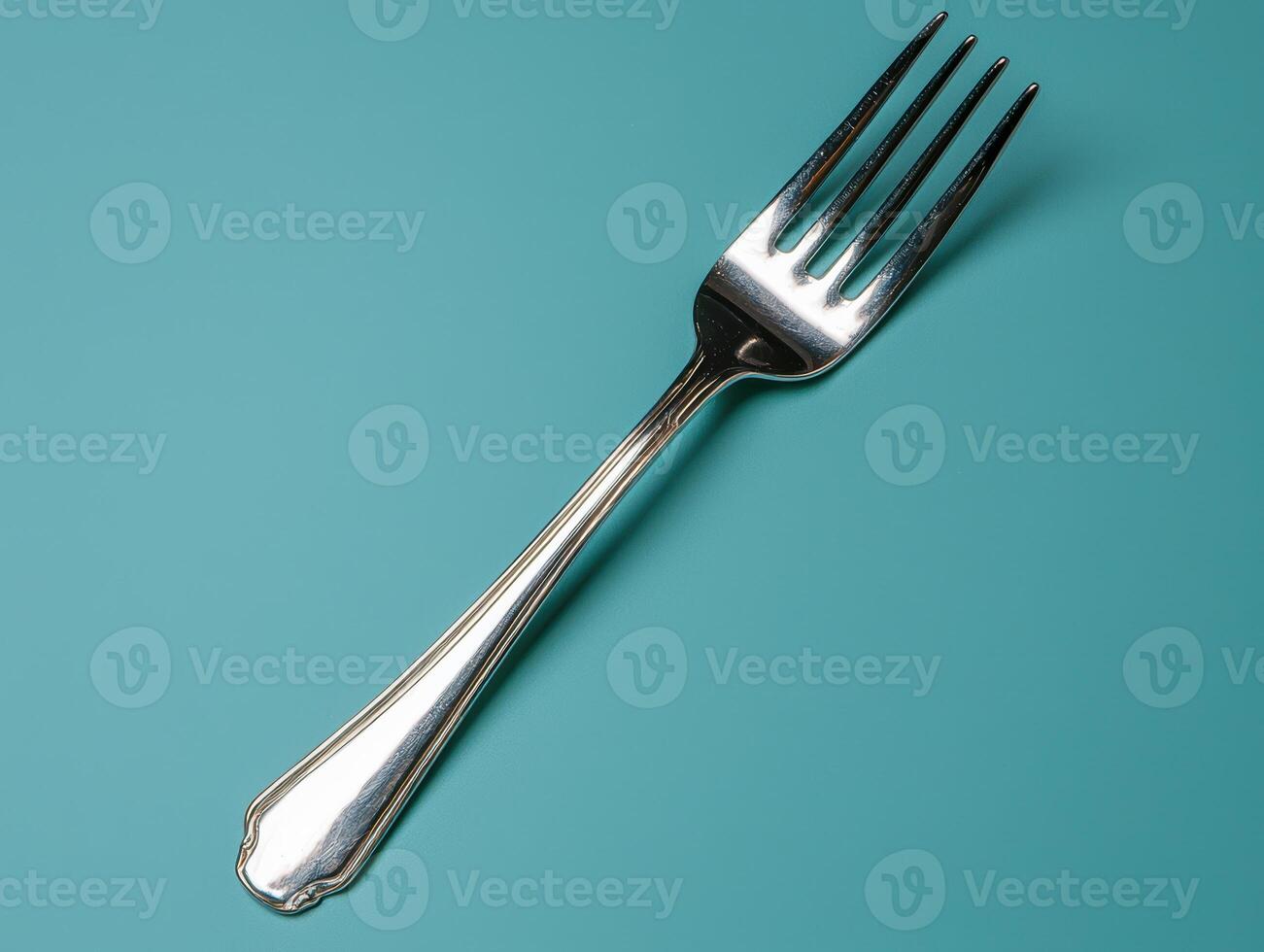 Silver fork on a teal background. photo