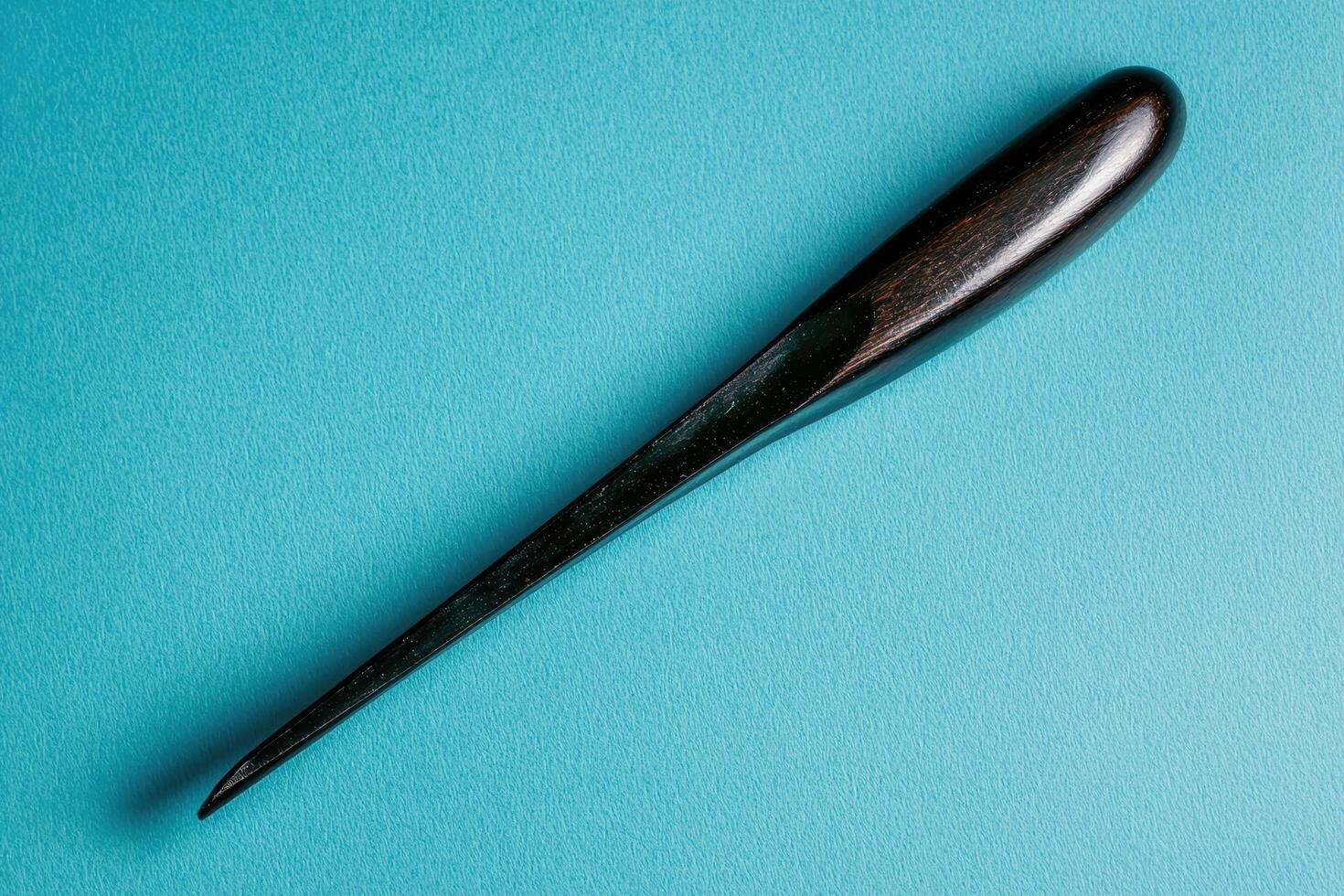Close up of a dark brown wooden tool on a teal background photo